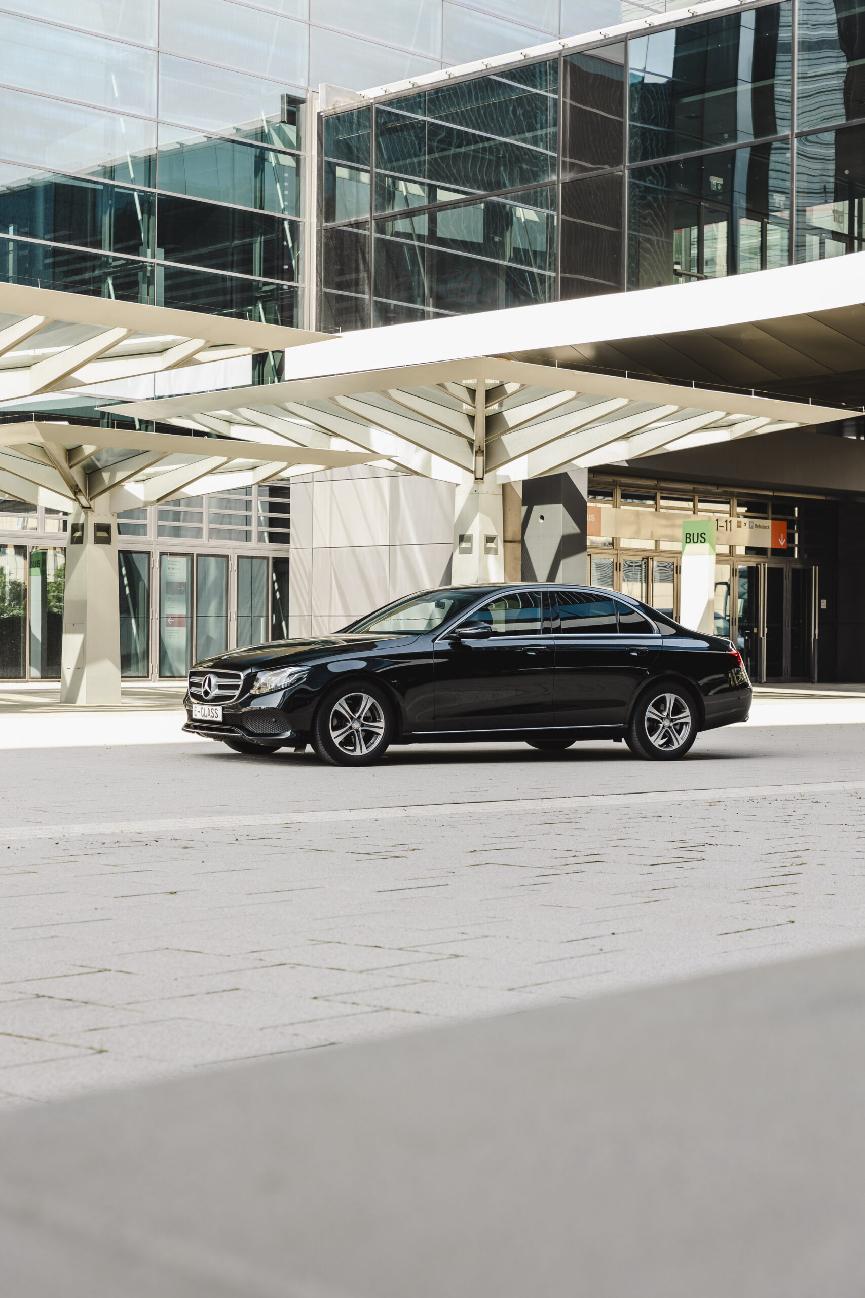 Schwarze Mercedes E-Klasse mit Chauffeur vor dem Flughafen Frankfurt.